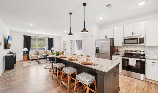 Large kitchen with island and seating for three open to the living room area in the Belmonte floor plan