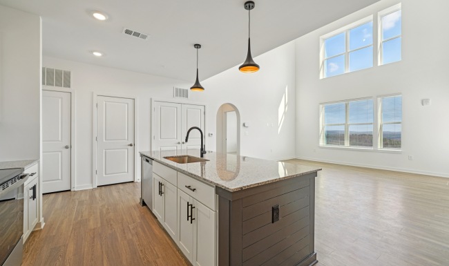 Kitchen island open to the living room showcasing the large floor to ceiling windows in the Brisa Loft floor plan Colina Hillside