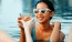 a woman in a pool holding a drink and a glass